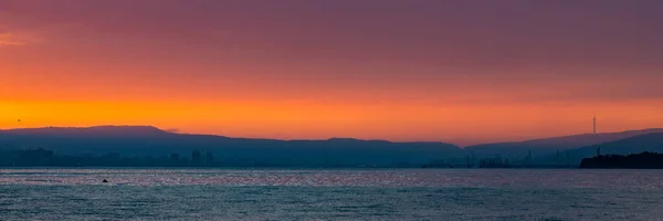 Coucher de soleil rouge vif sur la ville et les montagnes — Photo