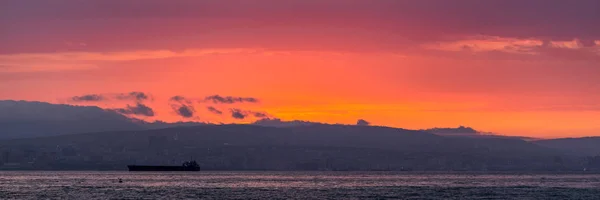 Şehir ve dağların üzerinde parlak kırmızı günbatımı gökyüzü — Stok fotoğraf