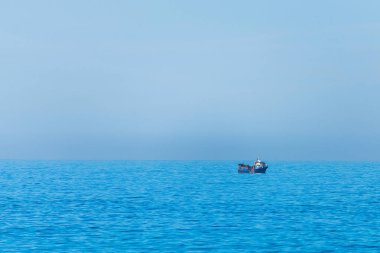 Bir balıkçı teknesi ile deniz minimalist görüntü. Mavi deniz suyu ve berrak gökyüzü.