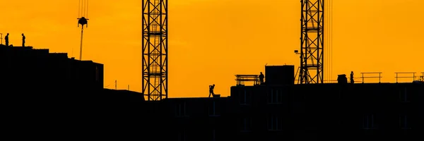 Achtergrond silhouet gebouw kraan hijslast met zonsondergang stralen geel bewolkt avond hemel achtergrond Bouwplaats bij oranje zonsondergang — Stockfoto