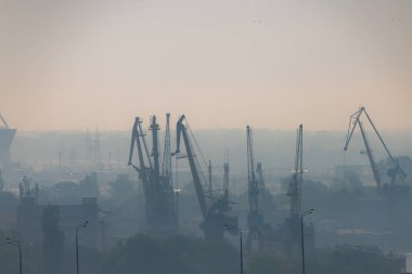 Nehir limanında hava kirliliği. Şehirde sanayi alanında sabah sis portal vinç. Solunum hastalıklarını toz nedenleri ile dolu kötü hava kalitesi.