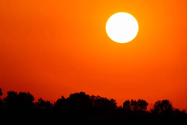 Sol brillante en un cielo naranja con nubes al atardecer — Foto de Stock