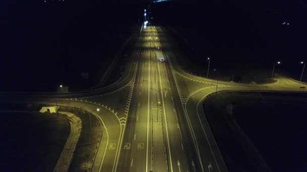 Luchtfoto van een nachtelijk kruispunt met een auto. Uitzicht vanaf de drone van de nacht snelweg met nachtverkeer — Stockvideo