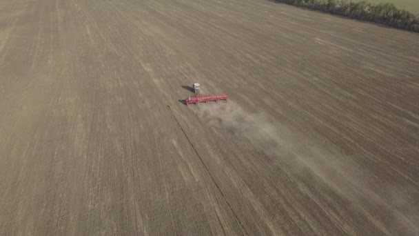 Tracteur sur chenilles cultive le sol dans un champ agricole. Vue aérienne du drone en vidéo 4k