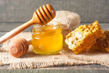 Tatlım gelen ahşap bal ayı gri rustik ahşap arka plan üzerinde bir kavanoza damlama