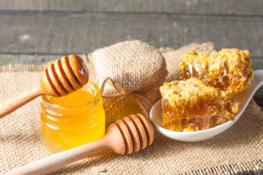 Tatlım gelen ahşap bal ayı gri rustik ahşap arka plan üzerinde bir kavanoza damlama