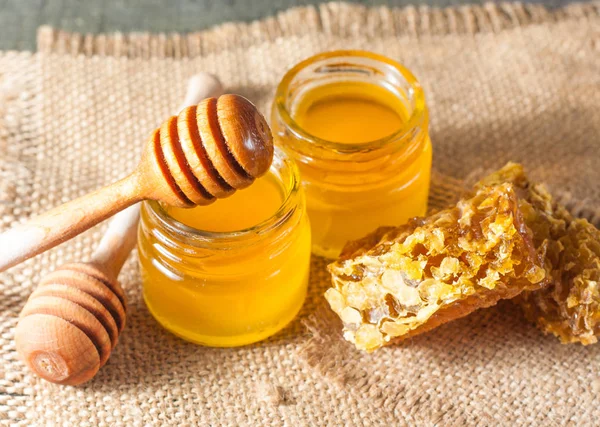 Tatlım gelen ahşap bal ayı gri rustik ahşap arka plan üzerinde bir kavanoza damlama