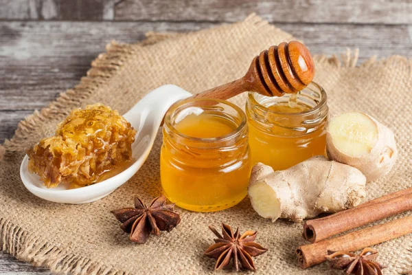 Tatlım gelen ahşap bal ayı gri rustik ahşap arka plan üzerinde bir kavanoza damlama