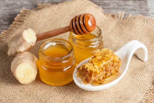 Tatlım gelen ahşap bal ayı gri rustik ahşap arka plan üzerinde bir kavanoza damlama