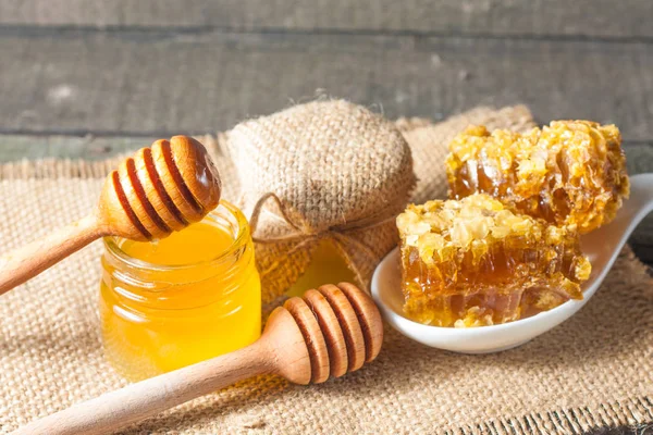 Tatlım gelen ahşap bal ayı gri rustik ahşap arka plan üzerinde bir kavanoza damlama