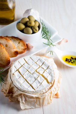 Pişmiş camembert peyniri. Taze Brie peyniri ve bir dilim fındık, tatlım, biberiye ile ahşap bir gemide, baget ekmek ızgara tost ve yaprakları. Peynir Brie türü. İtalyan, Fransız peynir.