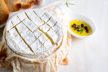Pişmiş camembert peyniri. Taze Brie peyniri ve bir dilim fındık, tatlım, biberiye ile ahşap bir gemide, baget ekmek ızgara tost ve yaprakları. Peynir Brie türü. İtalyan, Fransız peynir.