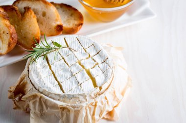 Pişmiş camembert peyniri. Taze Brie peyniri ve bir dilim fındık, tatlım, biberiye ile ahşap bir gemide, baget ekmek ızgara tost ve yaprakları. Peynir Brie türü. İtalyan, Fransız peynir.