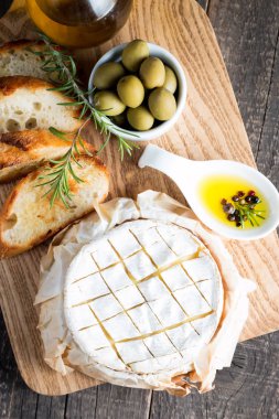 Pişmiş camembert peyniri. Taze Brie peyniri ve bir dilim fındık, tatlım, biberiye ile ahşap bir gemide, baget ekmek ızgara tost ve yaprakları. Peynir Brie türü. İtalyan, Fransız peynir.