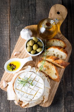 Pişmiş camembert peyniri. Taze Brie peyniri ve bir dilim fındık, tatlım, biberiye ile ahşap bir gemide, baget ekmek ızgara tost ve yaprakları. Peynir Brie türü. İtalyan, Fransız peynir.