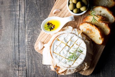 Pişmiş camembert peyniri. Taze Brie peyniri ve bir dilim fındık, tatlım, biberiye ile ahşap bir gemide, baget ekmek ızgara tost ve yaprakları. Peynir Brie türü. İtalyan, Fransız peynir.