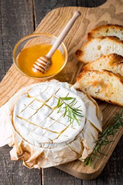 Pişmiş camembert peyniri. Taze Brie peyniri ve bir dilim fındık, tatlım, biberiye ile ahşap bir gemide, baget ekmek ızgara tost ve yaprakları. Peynir Brie türü. İtalyan, Fransız peynir.
