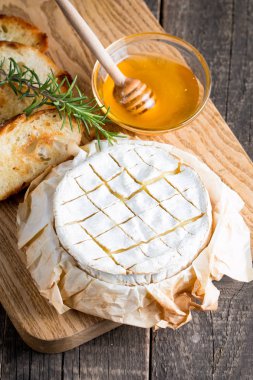 Pişmiş camembert peyniri. Taze Brie peyniri ve bir dilim fındık, tatlım, biberiye ile ahşap bir gemide, baget ekmek ızgara tost ve yaprakları. Peynir Brie türü. İtalyan, Fransız peynir.
