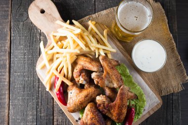 Yakın çekim fotoğraf Barbekü tavuk kanatlı patates ve bira. Barbekü soslar, ketçap, mayonez etli. Hızlı ve abur cubur kavramı. 