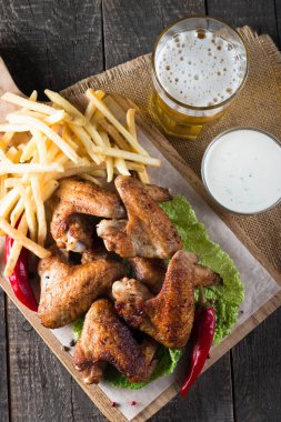 Yakın çekim fotoğraf Barbekü tavuk kanatlı patates ve bira. Barbekü soslar, ketçap, mayonez etli. Hızlı ve abur cubur kavramı. 