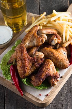 Yakın çekim fotoğraf Barbekü tavuk kanatlı patates ve bira. Barbekü soslar, ketçap, mayonez etli. Hızlı ve abur cubur kavramı. 