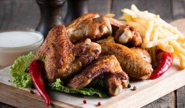 Yakın çekim fotoğraf Barbekü tavuk kanatlı patates ve bira. Barbekü soslar, ketçap, mayonez etli. Hızlı ve abur cubur kavramı. 