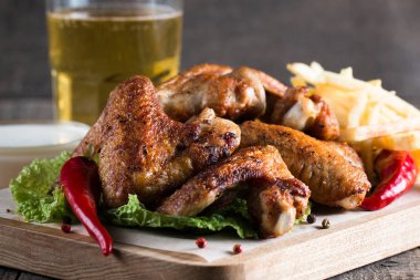 Yakın çekim fotoğraf Barbekü tavuk kanatlı patates ve bira. Barbekü soslar, ketçap, mayonez etli. Hızlı ve abur cubur kavramı. 