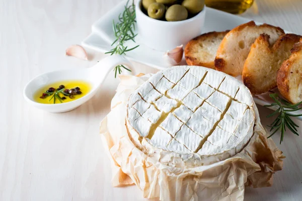 Pişmiş camembert peyniri. Taze Brie peyniri ve bir dilim fındık, tatlım, biberiye ile ahşap bir gemide, baget ekmek ızgara tost ve yaprakları. Peynir Brie türü. İtalyan, Fransız peynir.