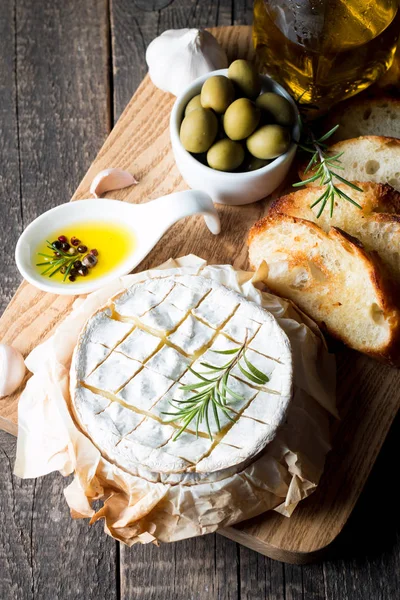 Pişmiş camembert peyniri. Taze Brie peyniri ve bir dilim fındık, tatlım, biberiye ile ahşap bir gemide, baget ekmek ızgara tost ve yaprakları. Peynir Brie türü. İtalyan, Fransız peynir.
