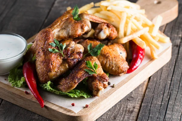 Yakın çekim fotoğraf Barbekü tavuk kanatlı patates ve bira. Barbekü soslar, ketçap, mayonez etli. Hızlı ve abur cubur kavramı. 