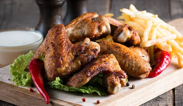 Yakın çekim fotoğraf Barbekü tavuk kanatlı patates ve bira. Barbekü soslar, ketçap, mayonez etli. Hızlı ve abur cubur kavramı. 