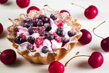 Taze meyve ve meyve ahşap zemin üzerine atmak şekerli tatlı tart. Ahududu, incir, çilek, kiraz ve krema ile lezzetli tatlı pasta.