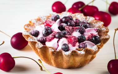 Taze meyve ve meyve ahşap zemin üzerine atmak şekerli tatlı tart. Ahududu, incir, çilek, kiraz ve krema ile lezzetli tatlı pasta.