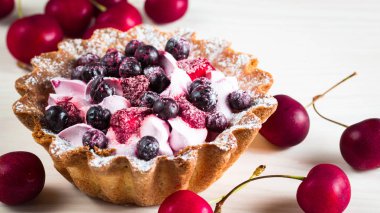 Taze meyve ve meyve ahşap zemin üzerine atmak şekerli tatlı tart. Ahududu, incir, çilek, kiraz ve krema ile lezzetli tatlı pasta.