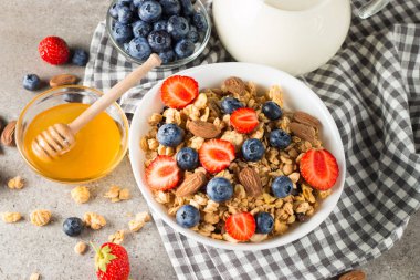 Sağlıklı kahvaltı konsepti ile yulaf gevreği ve rustik arka plan üzerinde taze çilek. Granola yapılan yemekleri müsli. Böğürtlen, muslie, çilek, yaban mersini ve bal ile sağlıklı muz smoothie.