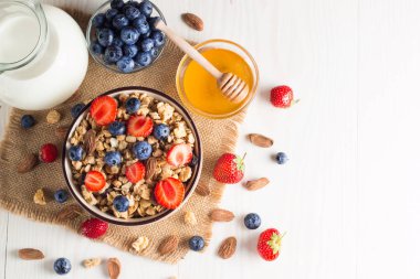 Sağlıklı kahvaltı konsepti ile yulaf gevreği ve rustik arka plan üzerinde taze çilek. Granola yapılan yemekleri müsli. Böğürtlen, muslie, çilek, yaban mersini ve bal ile sağlıklı muz smoothie.