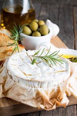 Pişmiş camembert peyniri. Taze Brie peyniri ve bir dilim fındık, tatlım, biberiye ile ahşap bir gemide, baget ekmek ızgara tost ve yaprakları. Peynir Brie türü. İtalyan, Fransız peynir.