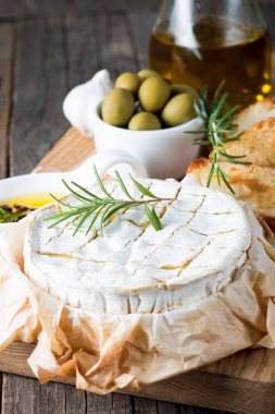 Pişmiş camembert peyniri. Taze Brie peyniri ve bir dilim fındık, tatlım, biberiye ile ahşap bir gemide, baget ekmek ızgara tost ve yaprakları. Peynir Brie türü. İtalyan, Fransız peynir.