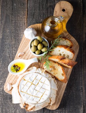 Pişmiş camembert peyniri. Taze Brie peyniri ve bir dilim fındık, tatlım, biberiye ile ahşap bir gemide, baget ekmek ızgara tost ve yaprakları. Peynir Brie türü. İtalyan, Fransız peynir.