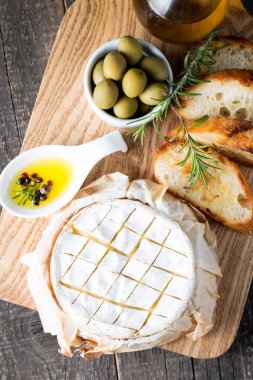 Pişmiş camembert peyniri. Taze Brie peyniri ve bir dilim fındık, tatlım, biberiye ile ahşap bir gemide, baget ekmek ızgara tost ve yaprakları. Peynir Brie türü. İtalyan, Fransız peynir.