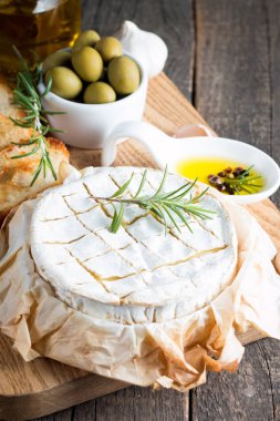 Pişmiş camembert peyniri. Taze Brie peyniri ve bir dilim fındık, tatlım, biberiye ile ahşap bir gemide, baget ekmek ızgara tost ve yaprakları. Peynir Brie türü. İtalyan, Fransız peynir.