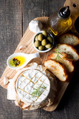 Pişmiş camembert peyniri. Taze Brie peyniri ve bir dilim fındık, tatlım, biberiye ile ahşap bir gemide, baget ekmek ızgara tost ve yaprakları. Peynir Brie türü. İtalyan, Fransız peynir.