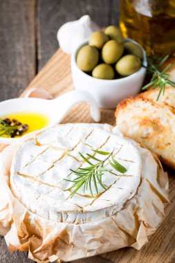 Pişmiş camembert peyniri. Taze Brie peyniri ve bir dilim fındık, tatlım, biberiye ile ahşap bir gemide, baget ekmek ızgara tost ve yaprakları. Peynir Brie türü. İtalyan, Fransız peynir.