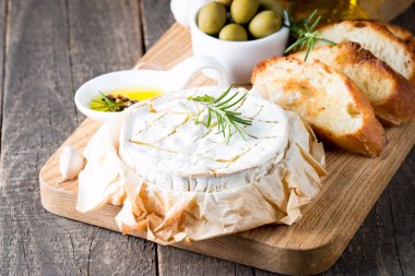 Pişmiş camembert peyniri. Taze Brie peyniri ve bir dilim fındık, tatlım, biberiye ile ahşap bir gemide, baget ekmek ızgara tost ve yaprakları. Peynir Brie türü. İtalyan, Fransız peynir.