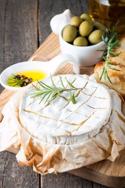 Pişmiş camembert peyniri. Taze Brie peyniri ve bir dilim fındık, tatlım, biberiye ile ahşap bir gemide, baget ekmek ızgara tost ve yaprakları. Peynir Brie türü. İtalyan, Fransız peynir.