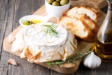 Pişmiş camembert peyniri. Taze Brie peyniri ve bir dilim fındık, tatlım, biberiye ile ahşap bir gemide, baget ekmek ızgara tost ve yaprakları. Peynir Brie türü. İtalyan, Fransız peynir.