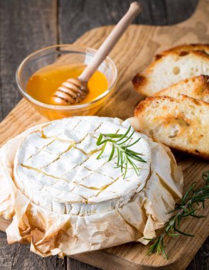 Pişmiş camembert peyniri. Taze Brie peyniri ve bir dilim fındık, tatlım, biberiye ile ahşap bir gemide, baget ekmek ızgara tost ve yaprakları. Peynir Brie türü. İtalyan, Fransız peynir.
