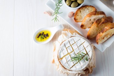 Pişmiş camembert peyniri. Taze Brie peyniri ve bir dilim fındık, tatlım, biberiye ile ahşap bir gemide, baget ekmek ızgara tost ve yaprakları. Peynir Brie türü. İtalyan, Fransız peynir.