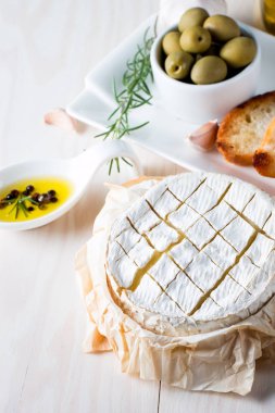 Pişmiş camembert peyniri. Taze Brie peyniri ve bir dilim fındık, tatlım, biberiye ile ahşap bir gemide, baget ekmek ızgara tost ve yaprakları. Peynir Brie türü. İtalyan, Fransız peynir.