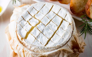 Pişmiş camembert peyniri. Taze Brie peyniri ve bir dilim fındık, tatlım, biberiye ile ahşap bir gemide, baget ekmek ızgara tost ve yaprakları. Peynir Brie türü. İtalyan, Fransız peynir.
